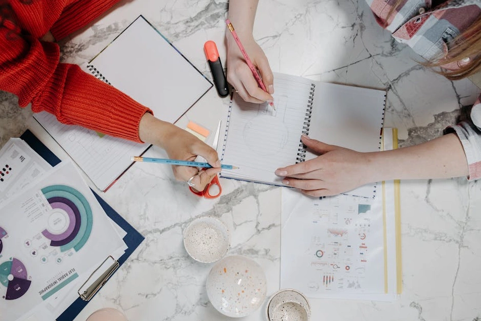 Persona che scrive su un taccuino durante una sessione di brainstorming creativo.